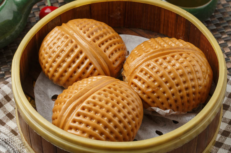 笼屉装的港式奶油菠萝包摆放在餐布上图片