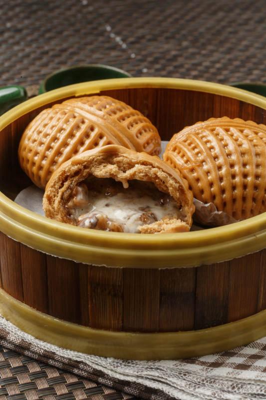 笼屉装的港式奶油菠萝包摆放在餐布上图片