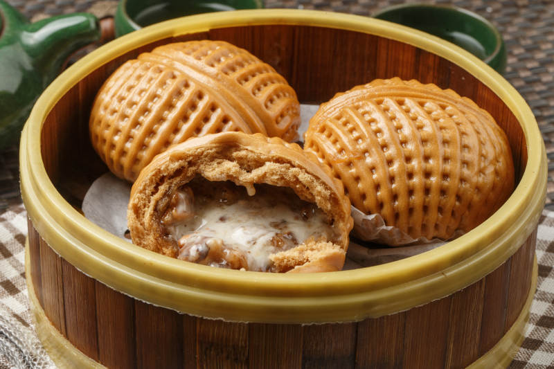 笼屉装的港式奶油菠萝包摆放在餐布上图片