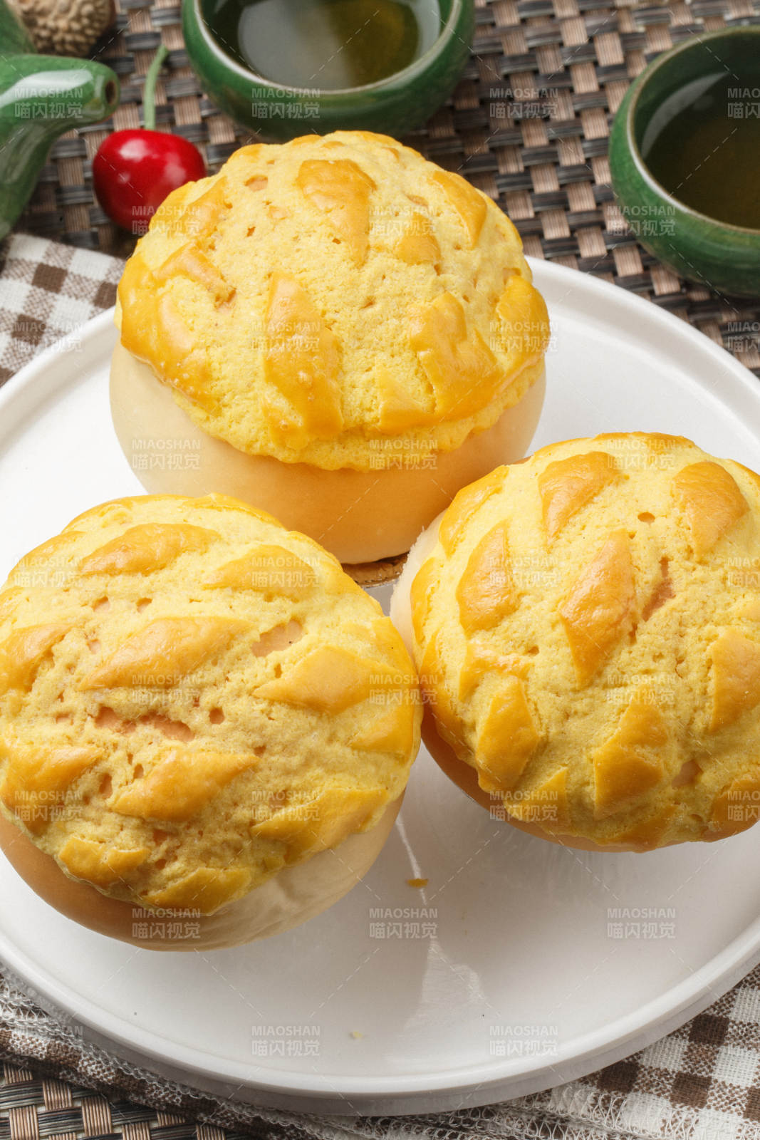 圆形白瓷盘装的酥皮菠萝包摆放在餐垫上图片