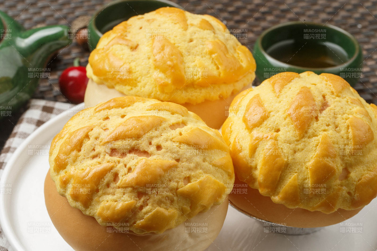 圆形白瓷盘装的酥皮菠萝包摆放在餐垫上图片