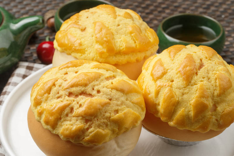 圆形白瓷盘装的酥皮菠萝包摆放在餐垫上图片