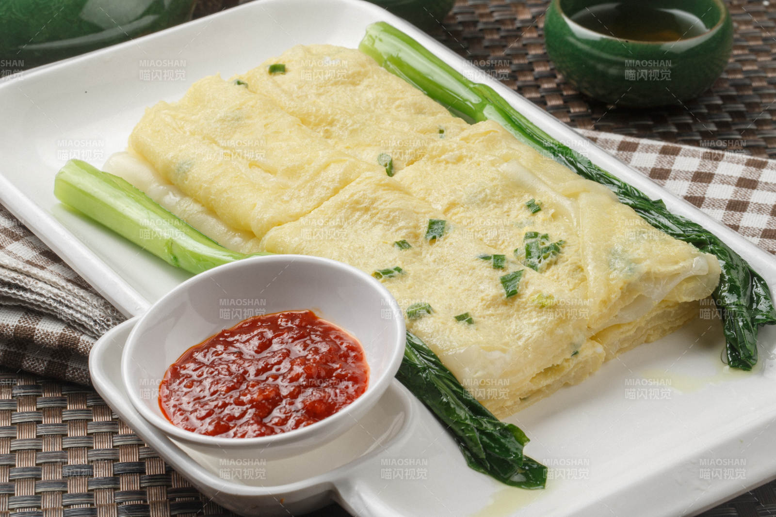 长方形白瓷盘装的港式蛋饼摆放在餐垫上图片