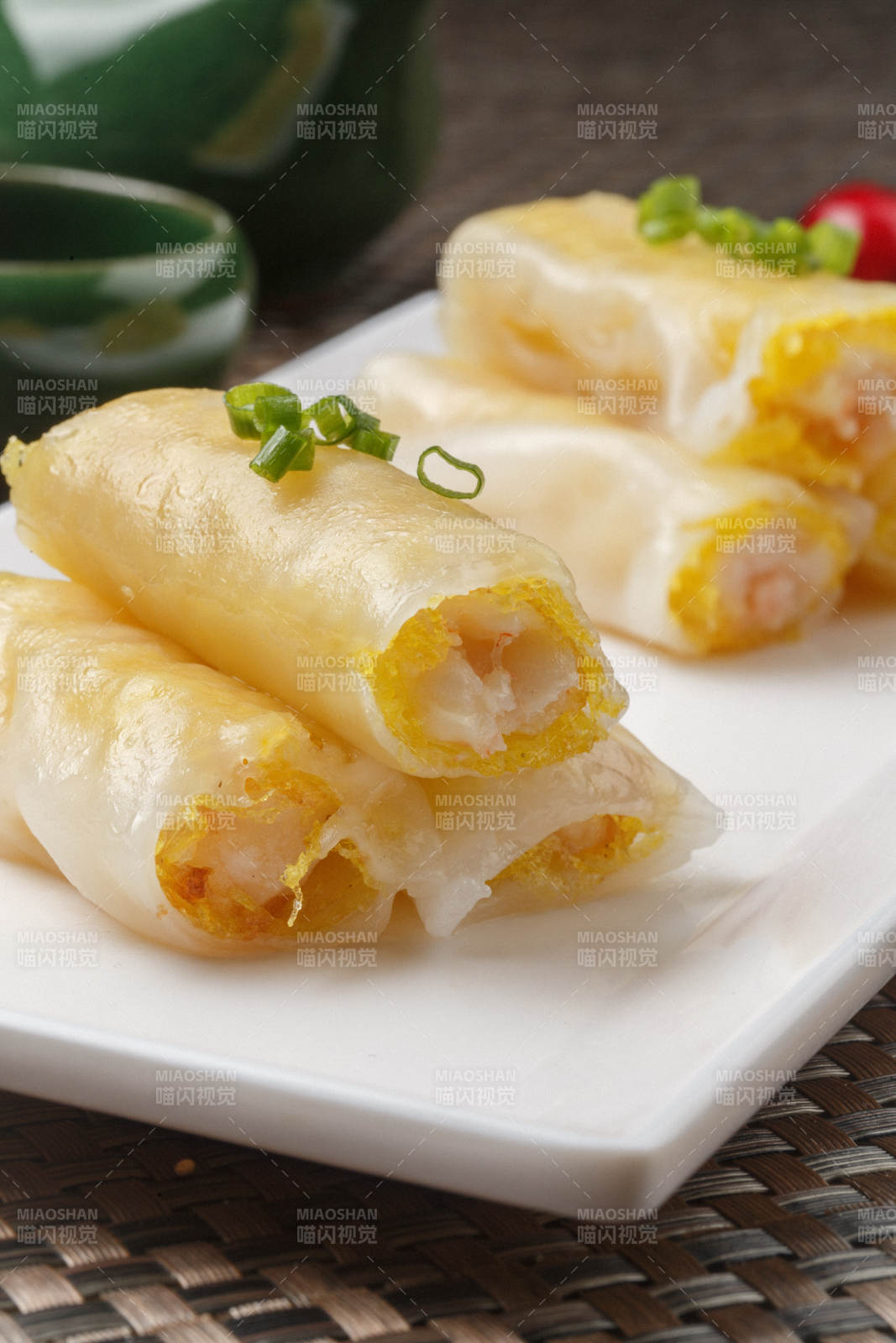 长方形白瓷盘装的虾仁肠粉摆放在餐垫上图片