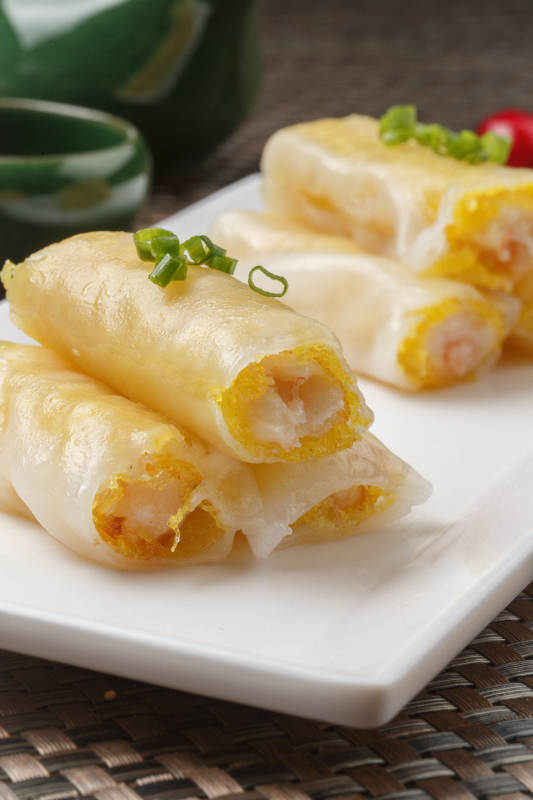 长方形白瓷盘装的虾仁肠粉摆放在餐垫上图片