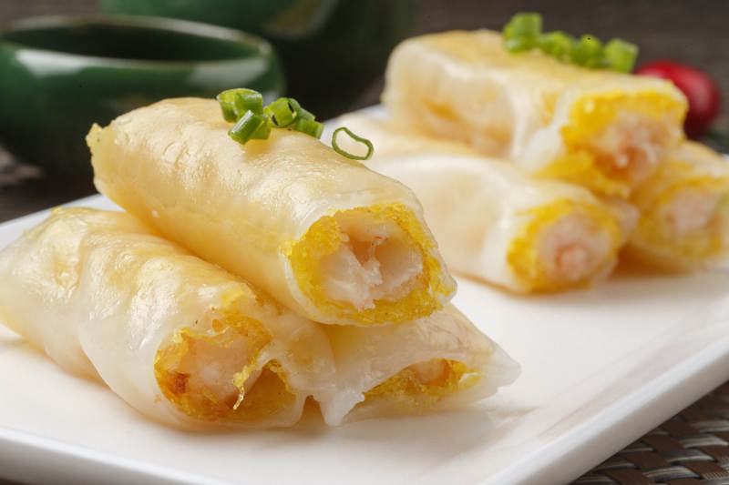 长方形白瓷盘装的虾仁肠粉摆放在餐垫上图片