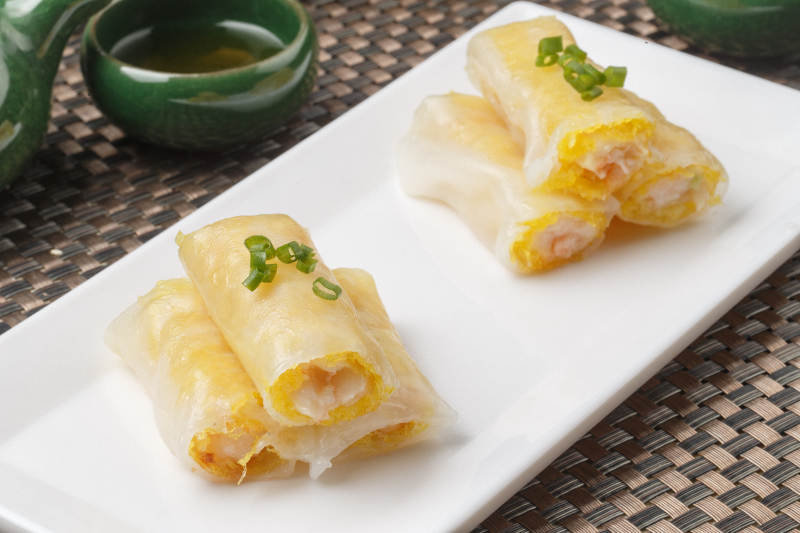 长方形白瓷盘装的虾仁肠粉摆放在餐垫上图片