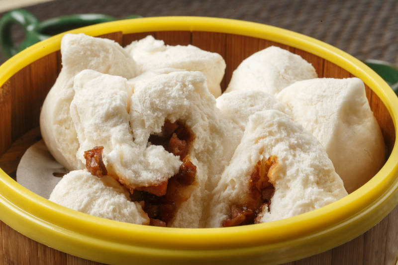 笼屉装的叉烧包摆放在餐垫上图片