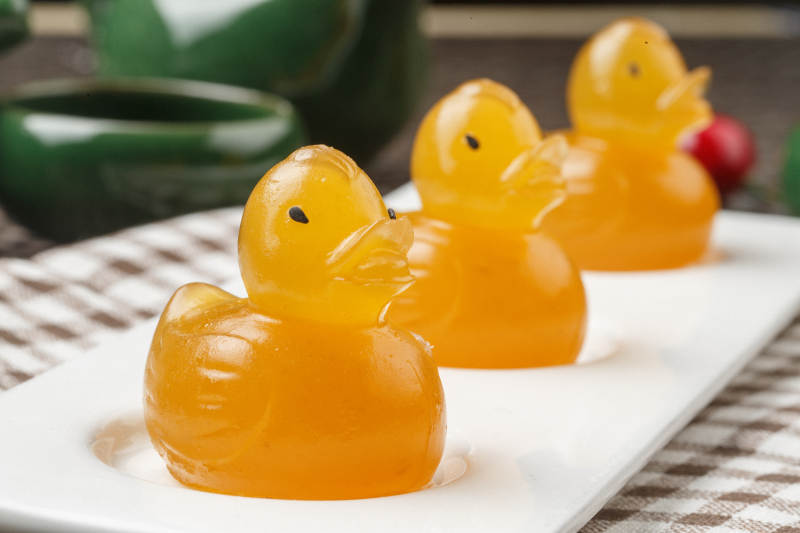 小黄鸭造型芒果糕摆放在餐布上图片