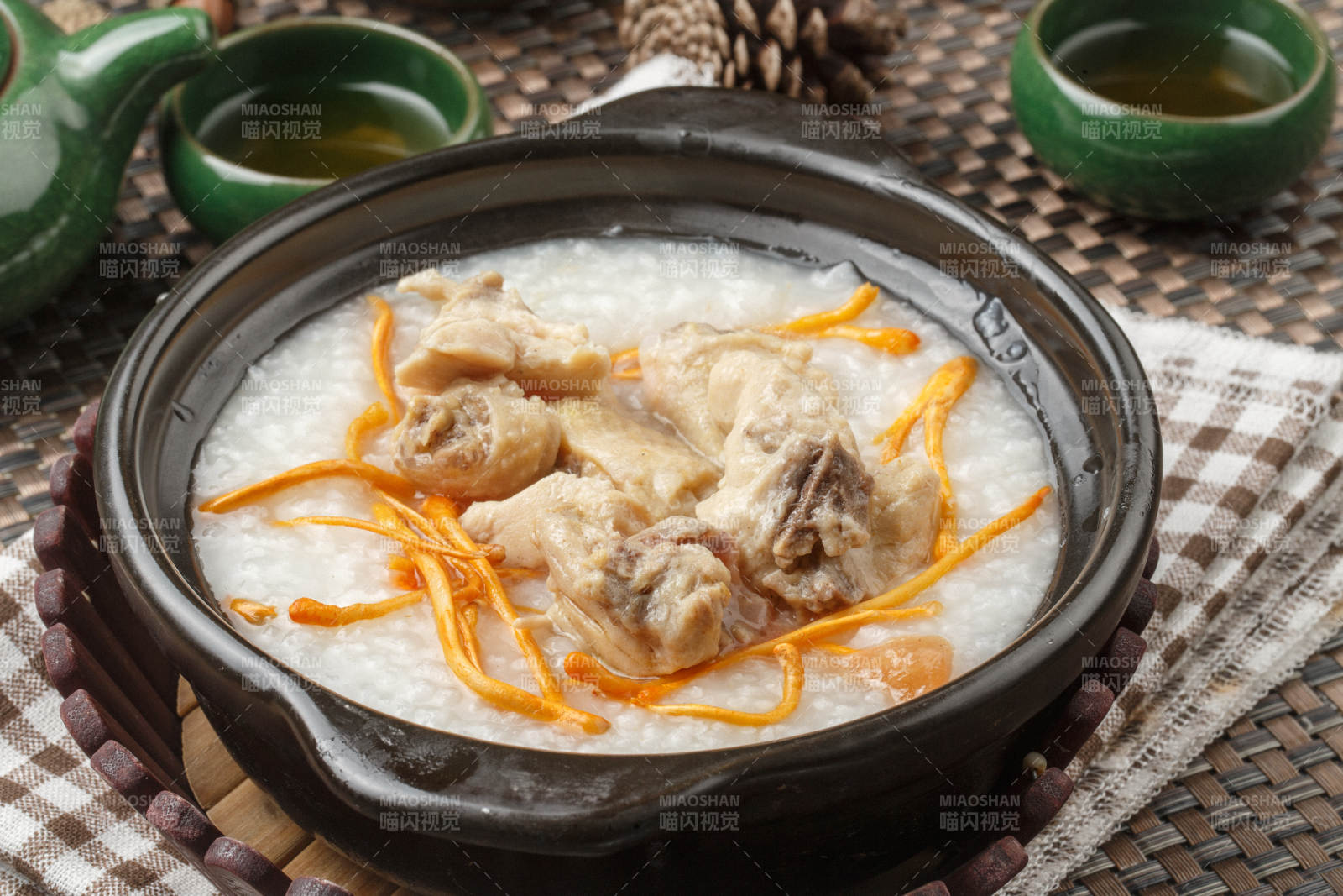 黑色砂锅装的虫草花排骨煲白粥摆放在餐布上图片
