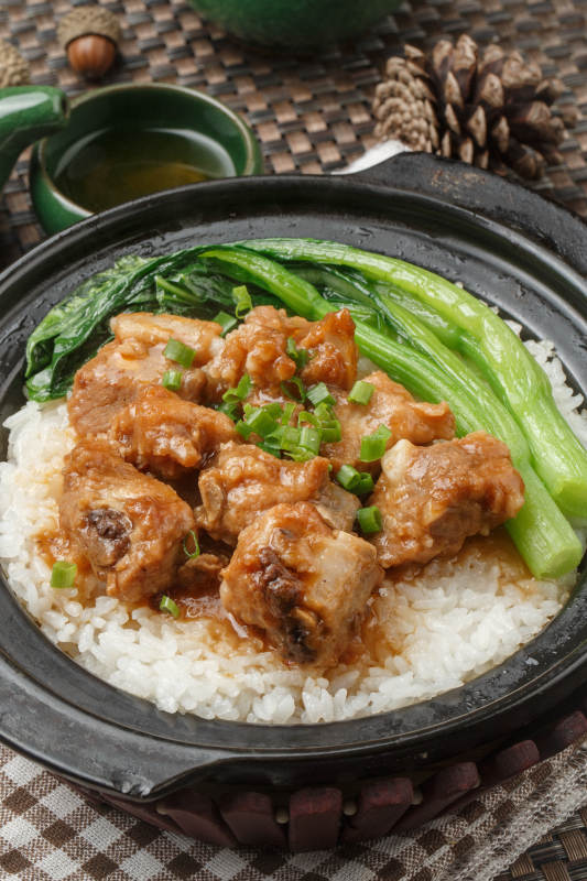 黑色砂锅装的虫草花排骨煲白粥摆放在餐布上图片