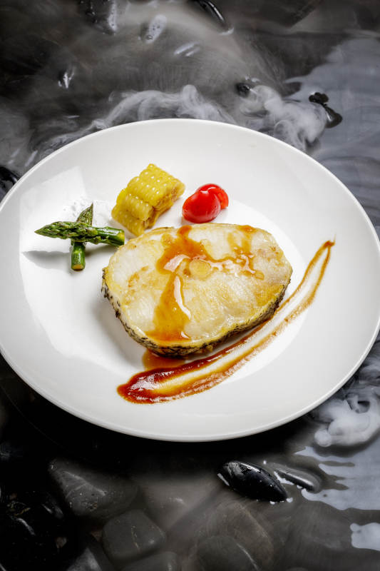 香煎银鳕鱼摆放在干冰缭绕的水中图片