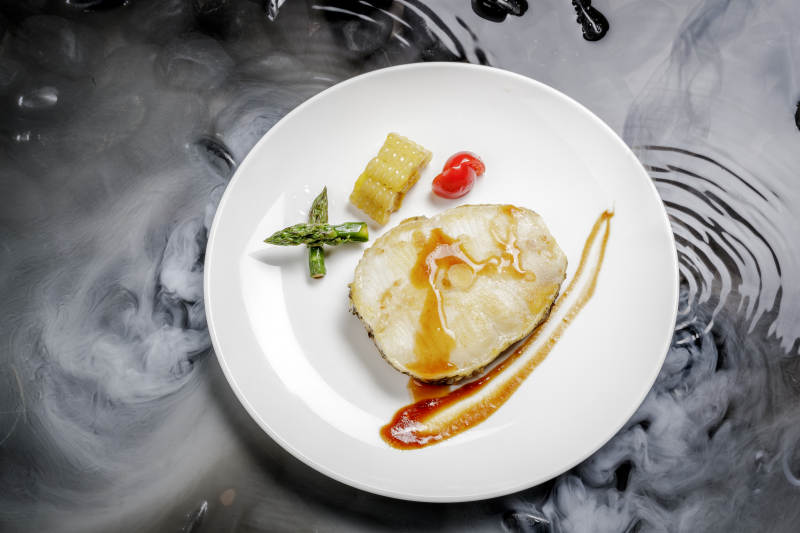 香煎银鳕鱼摆放在干冰缭绕的水中图片