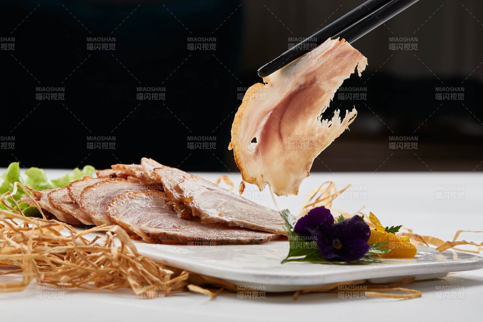 白色瓷盘装的烟熏猪肘五花肉图片