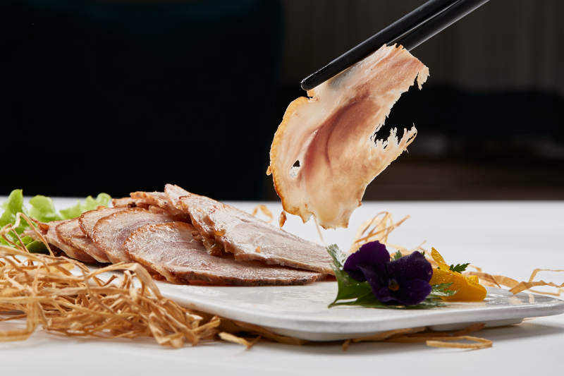 白色瓷盘装的烟熏猪肘五花肉图片