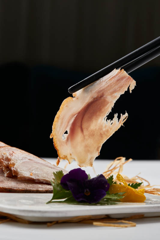 白色瓷盘装的烟熏猪肘五花肉图片