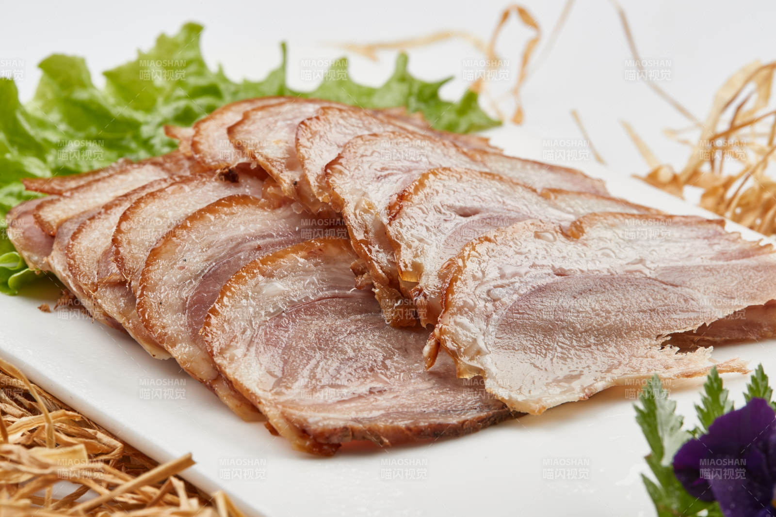 白色瓷盘装的烟熏猪肘五花肉图片