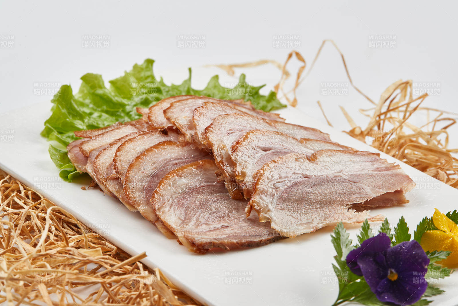 白色瓷盘装的烟熏猪肘五花肉图片