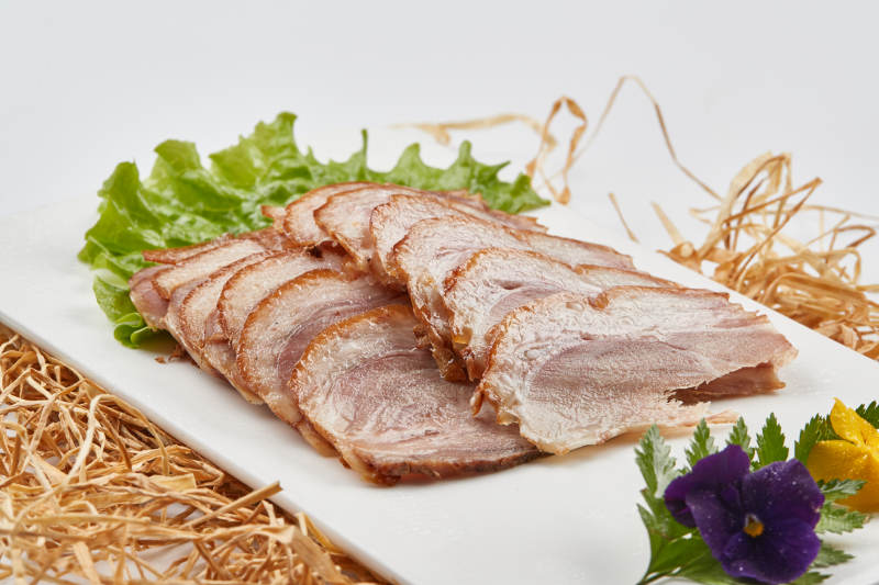 白色瓷盘装的烟熏猪肘五花肉图片