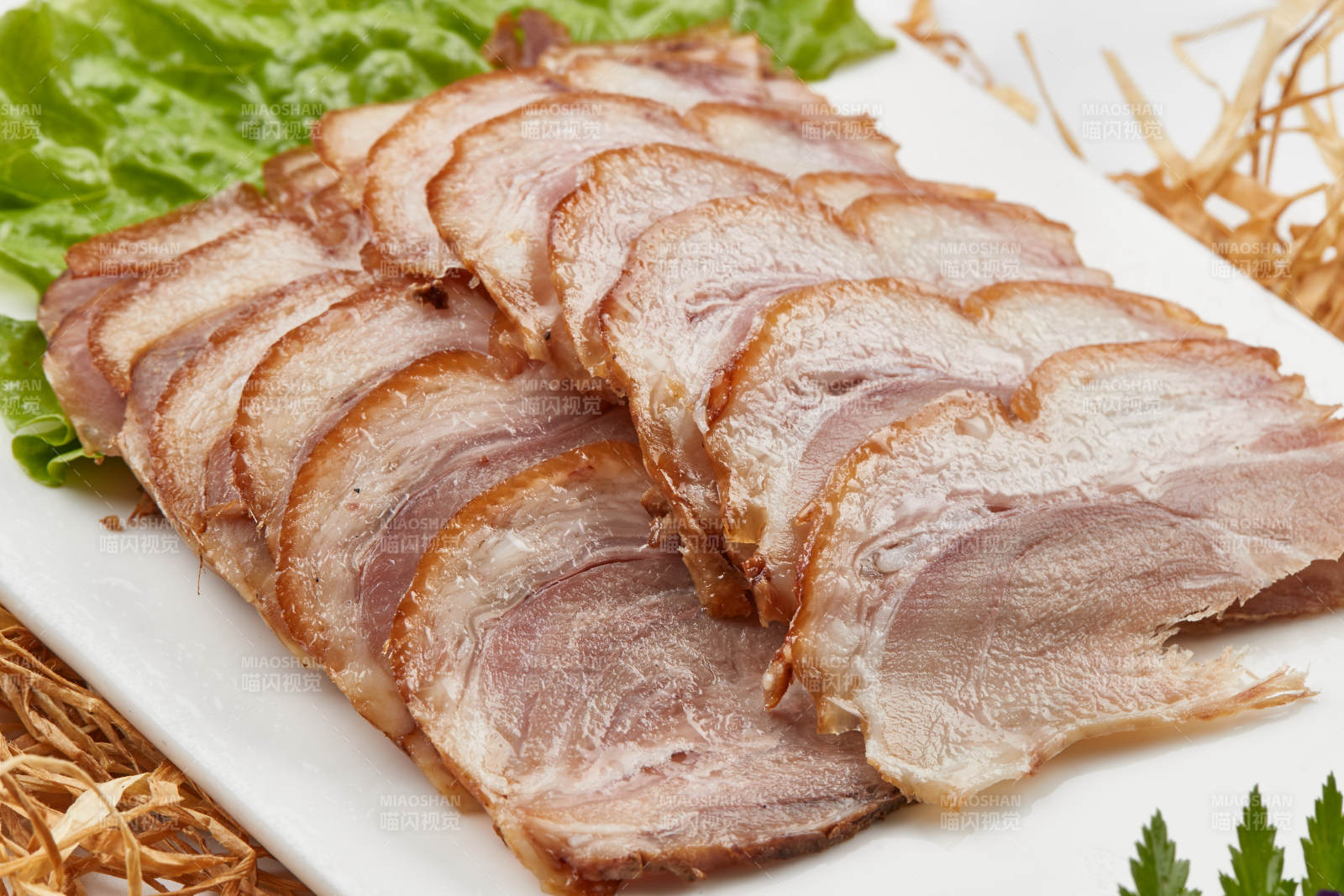 白色瓷盘装的烟熏猪肘五花肉图片