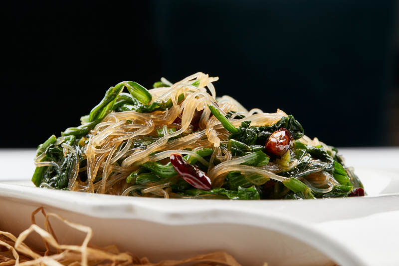 白色瓷盘装的凉拌粉丝菠菜图片