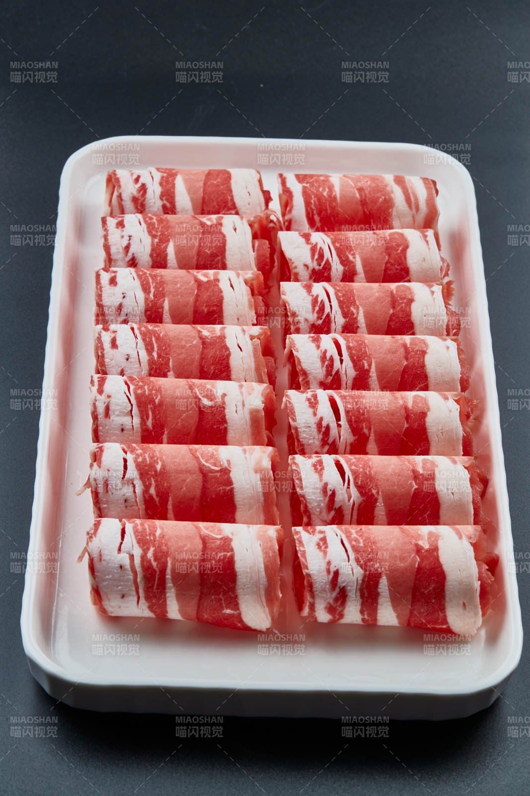 干冰缭绕的背景上摆放的草原肥羊肉卷图片