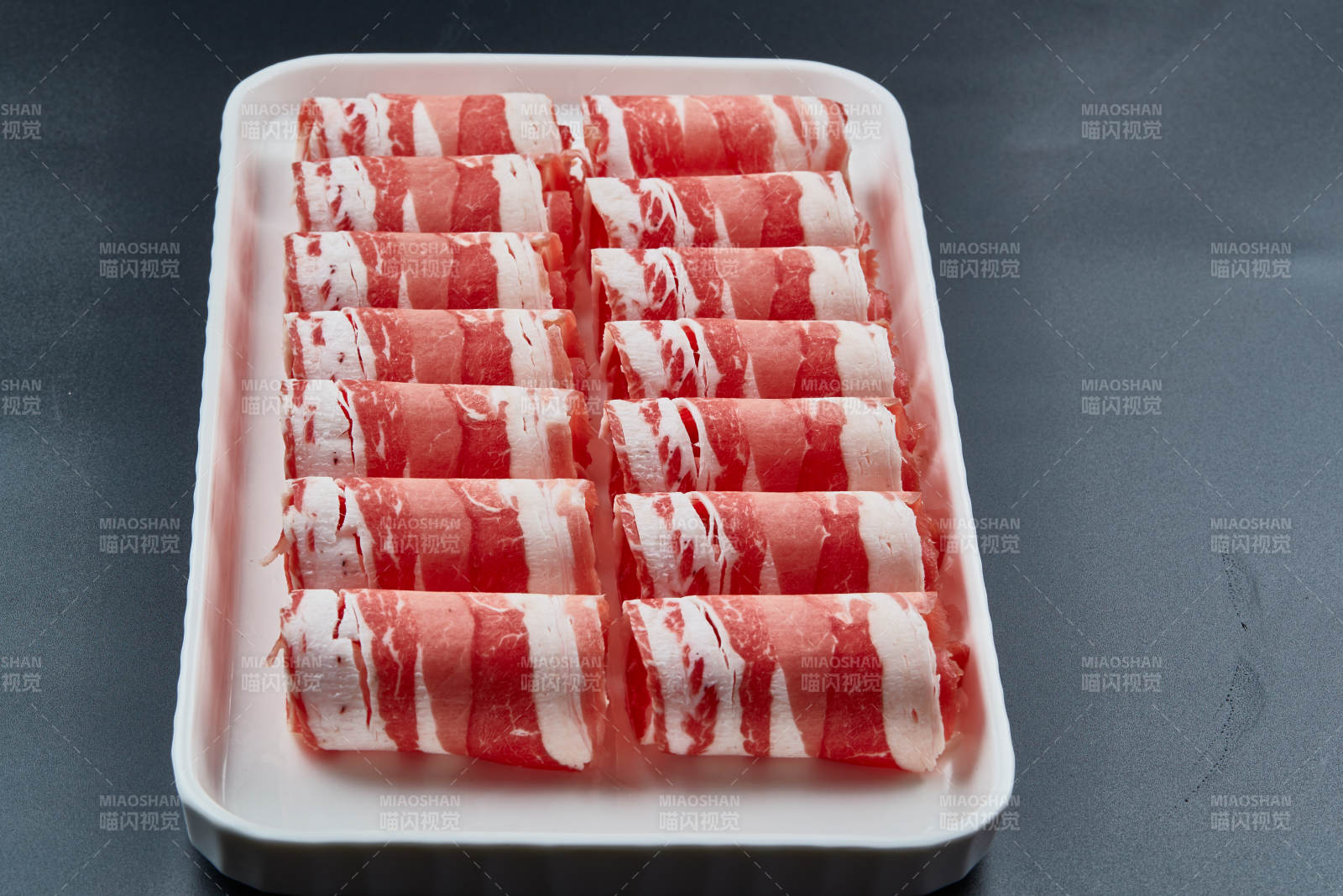 干冰缭绕的背景上摆放的草原肥羊肉卷图片