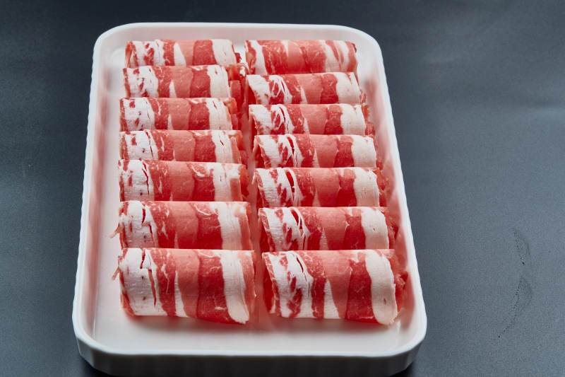 干冰缭绕的背景上摆放的草原肥羊肉卷图片