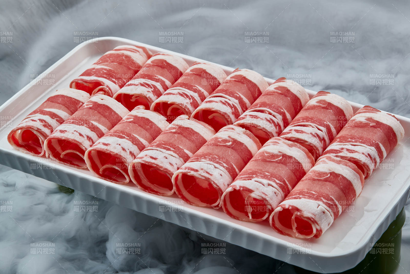 干冰缭绕的背景上摆放的草原肥羊肉卷图片