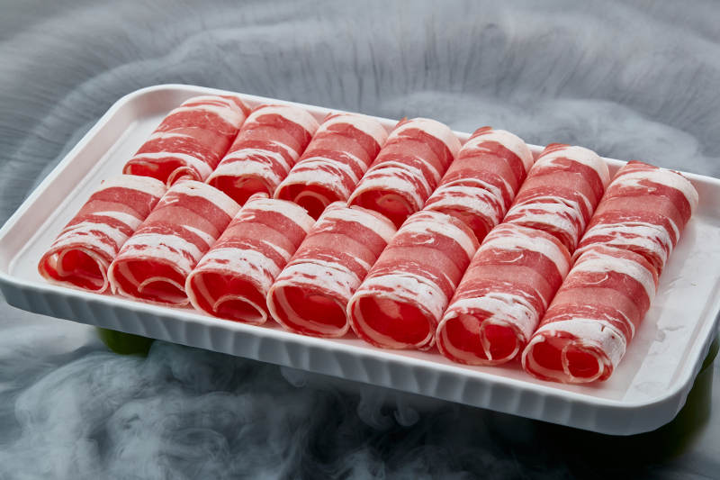 干冰缭绕的背景上摆放的草原肥羊肉卷图片