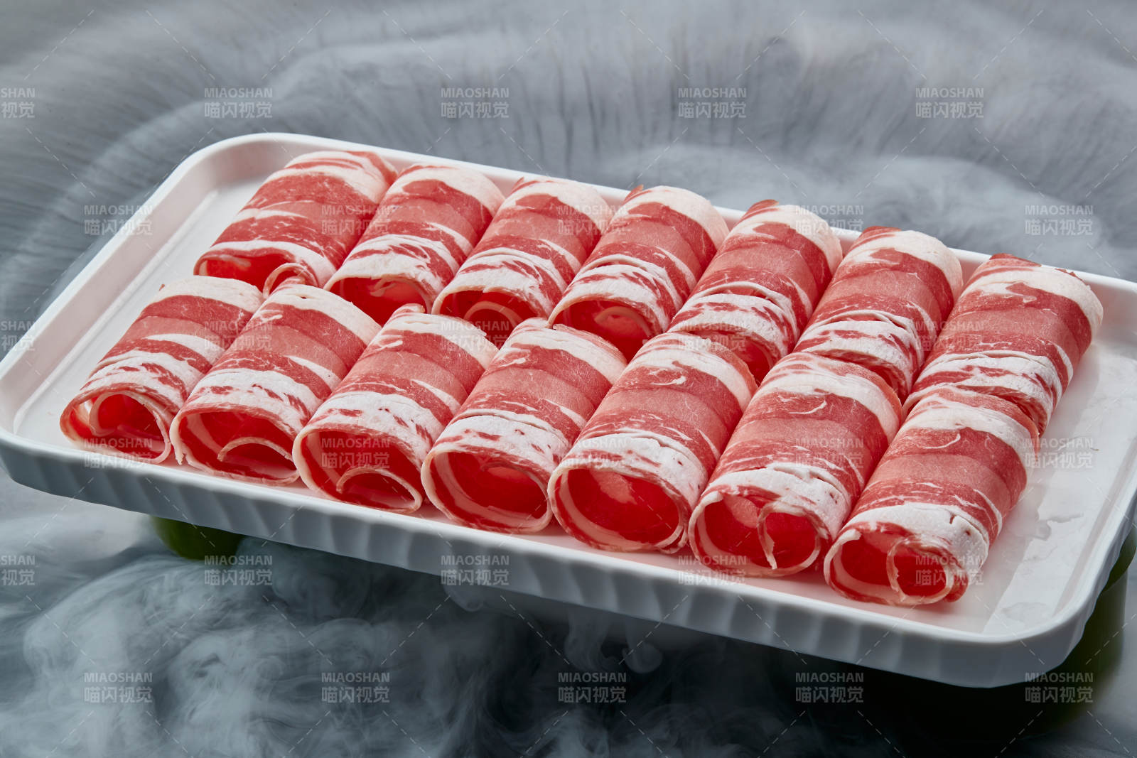 干冰缭绕的背景上摆放的草原肥羊肉卷图片