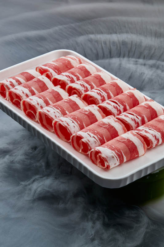 干冰缭绕的背景上摆放的草原肥羊肉卷图片