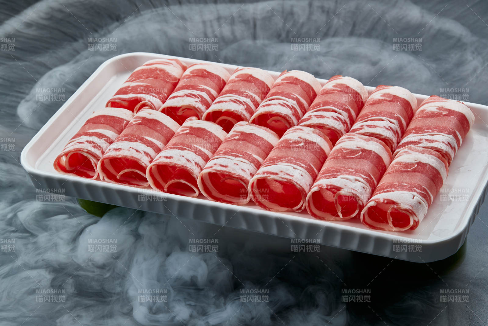 干冰缭绕的背景上摆放的草原肥羊肉卷图片