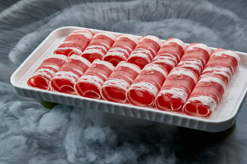 干冰缭绕的背景上摆放的草原肥羊肉卷图片