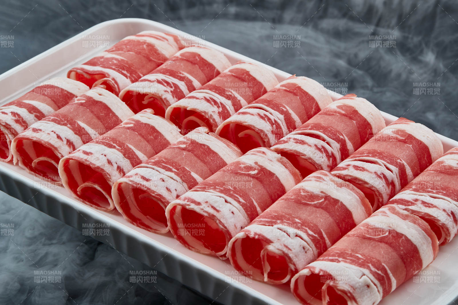 干冰缭绕的背景上摆放的草原肥羊肉卷图片