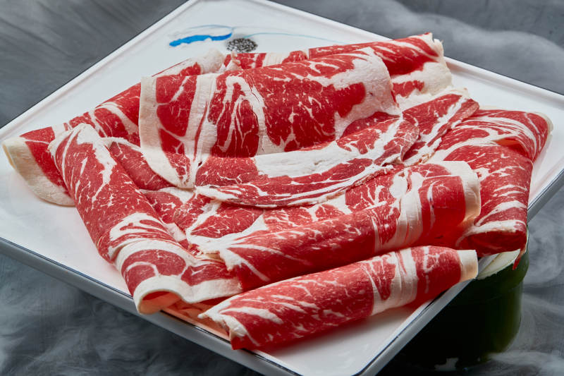 干冰缭绕的背景上摆放的上脑和牛切片图片