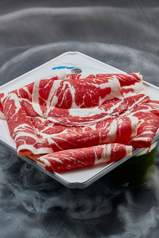 干冰缭绕的背景上摆放的上脑和牛切片图片