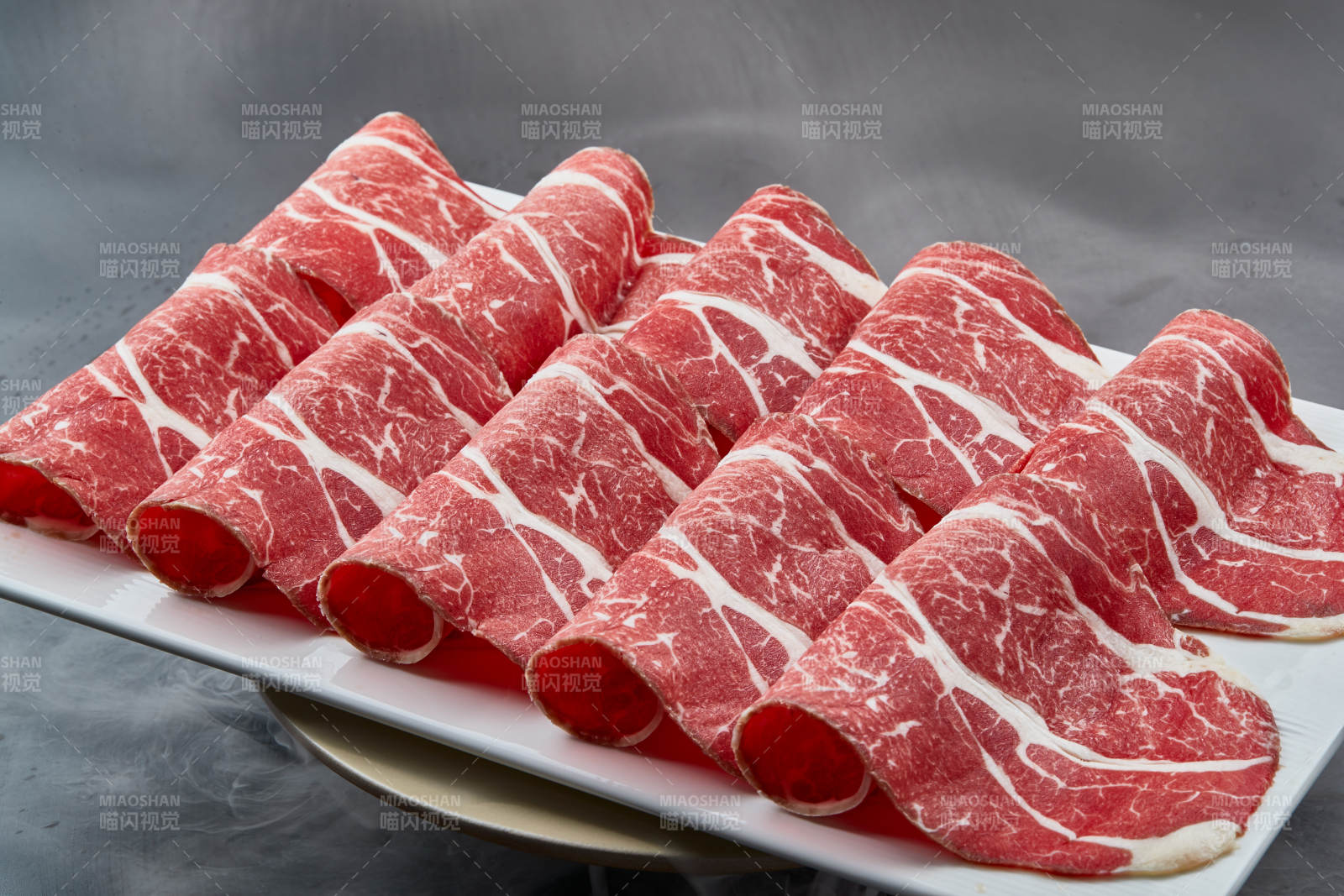 干冰缭绕的背景上摆放的高级雪花肥牛切片图片