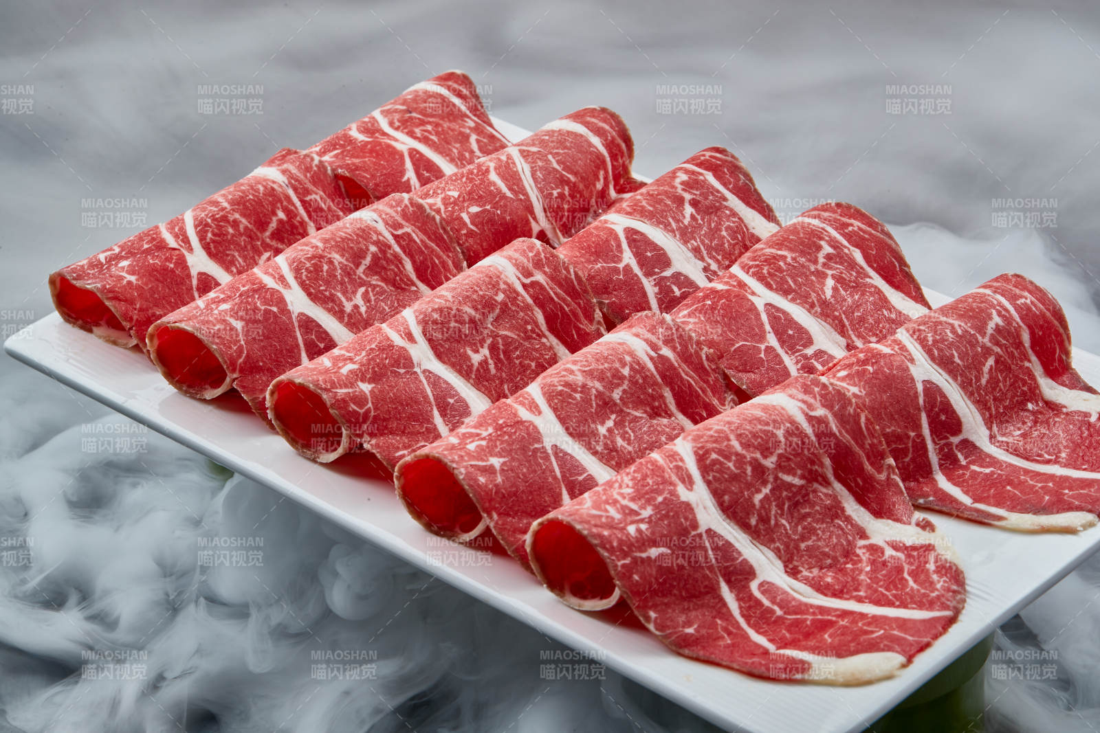 干冰缭绕的背景上摆放的高级雪花肥牛切片图片