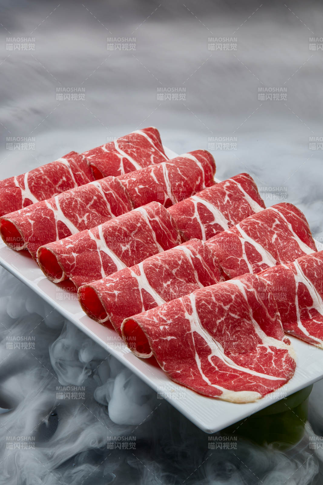 干冰缭绕的背景上摆放的高级雪花肥牛切片图片