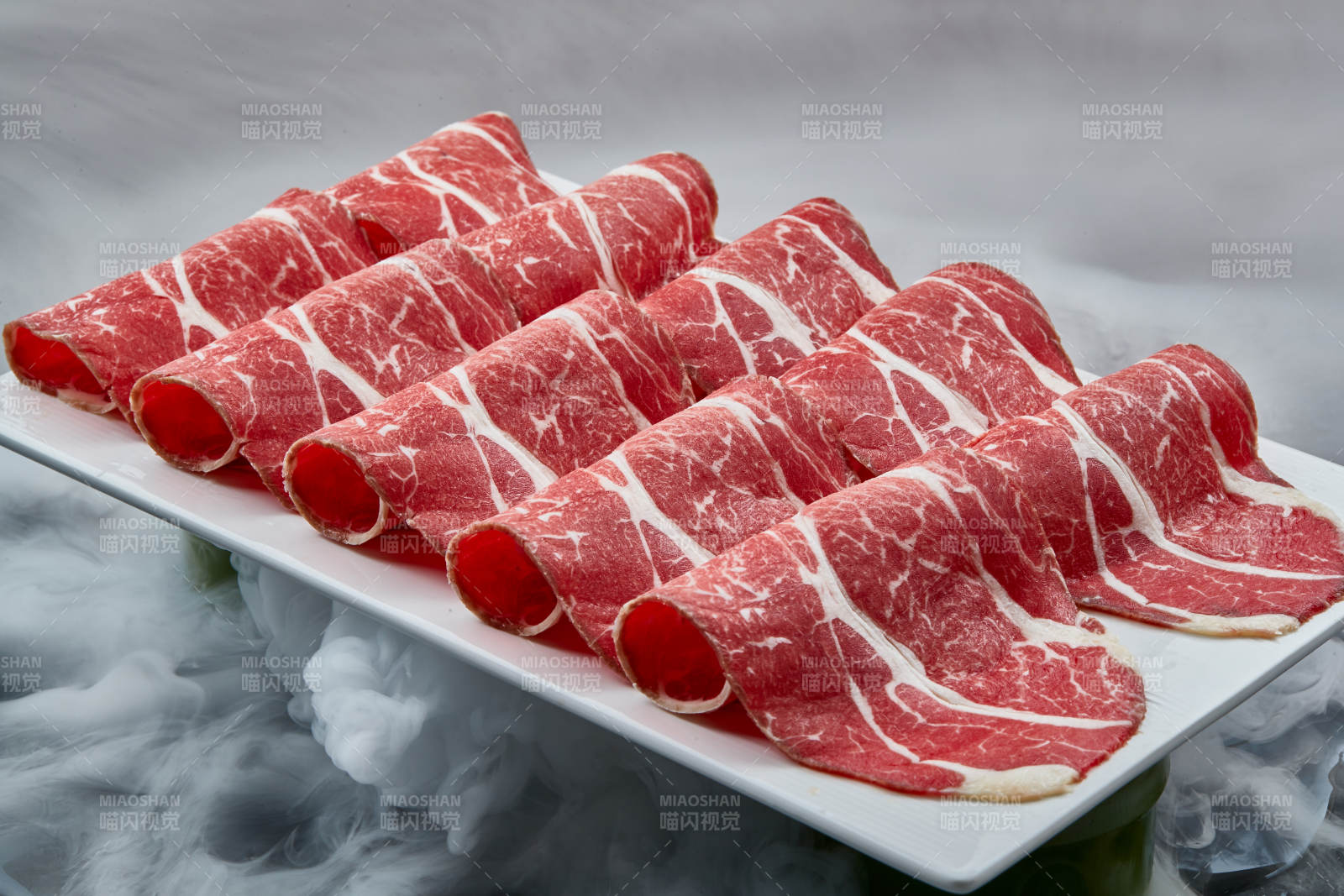 干冰缭绕的背景上摆放的高级雪花肥牛切片图片
