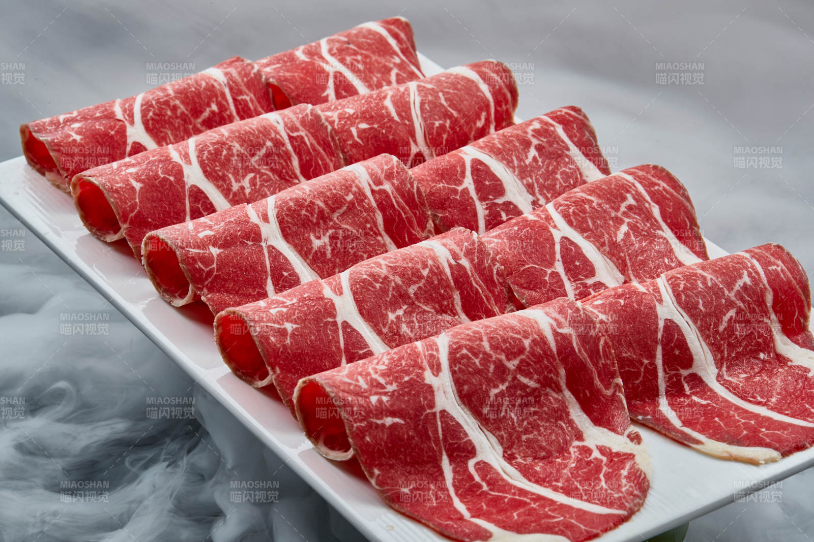 干冰缭绕的背景上摆放的高级雪花肥牛切片图片