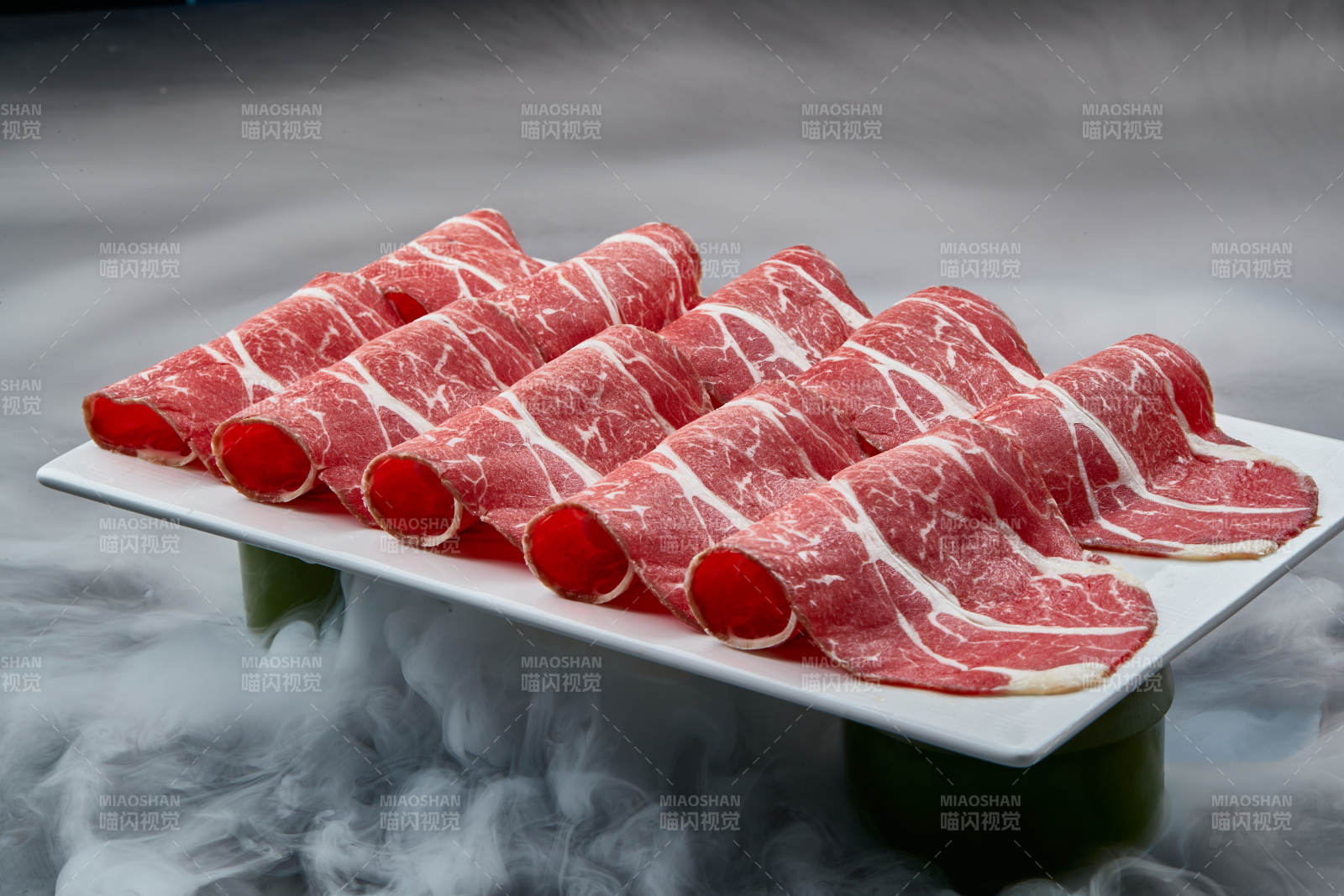 干冰缭绕的背景上摆放的高级雪花肥牛切片图片