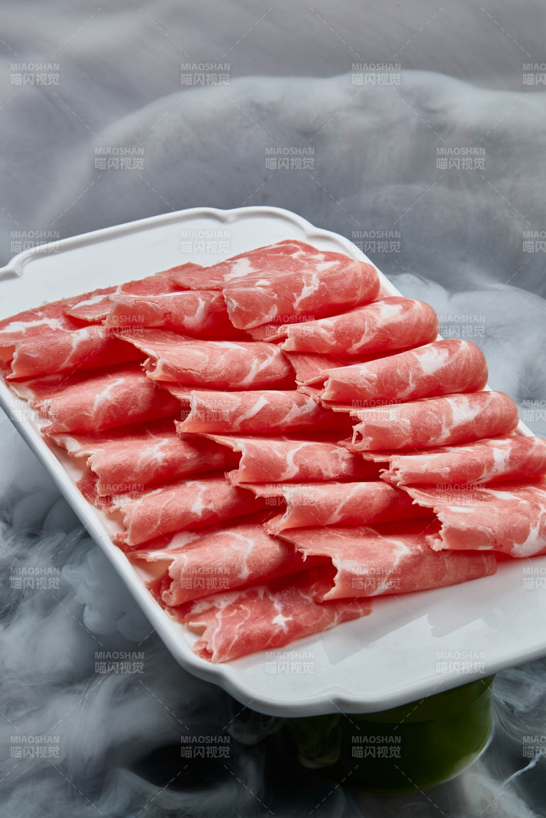 干冰缭绕的背景上摆放的牛肉切片图片