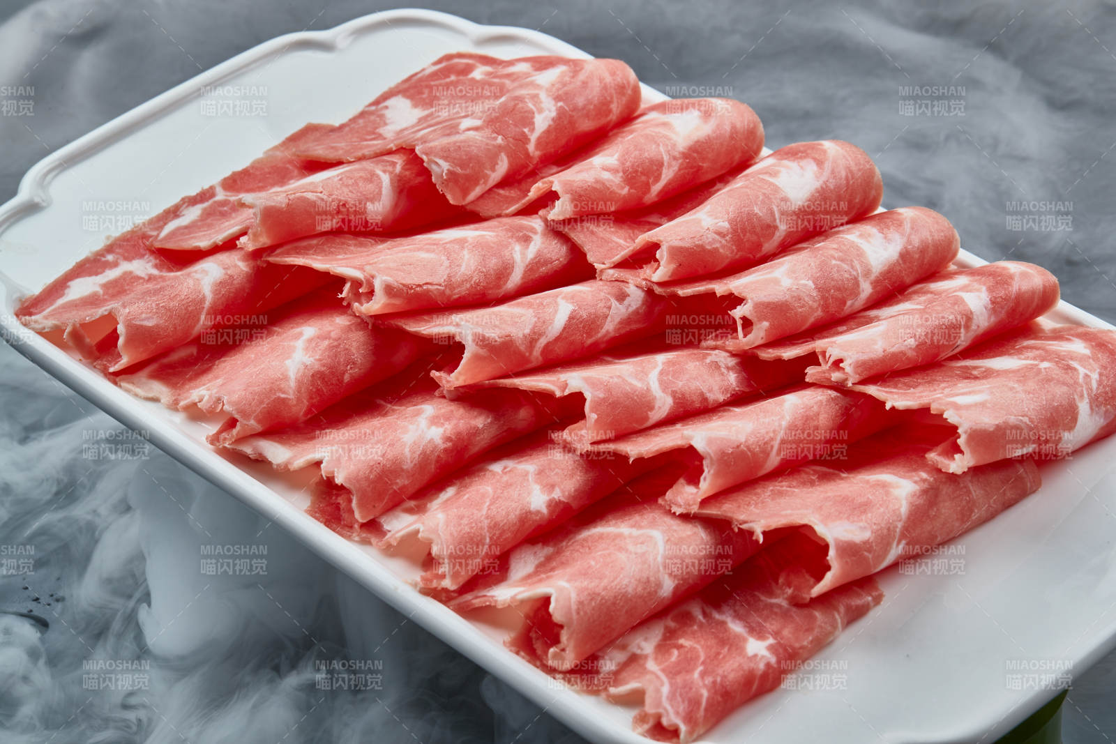 干冰缭绕的背景上摆放的牛肉切片图片