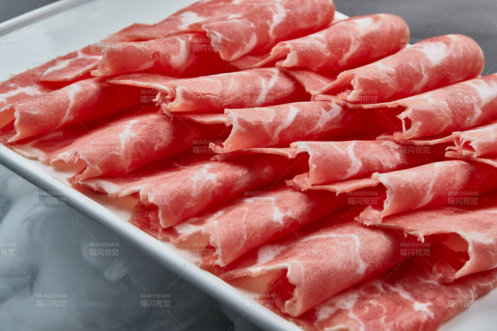 干冰缭绕的背景上摆放的牛肉切片图片