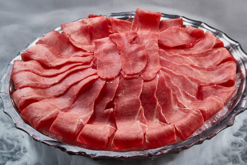 干冰缭绕的背景上摆放的鲜牛肉刺身图片