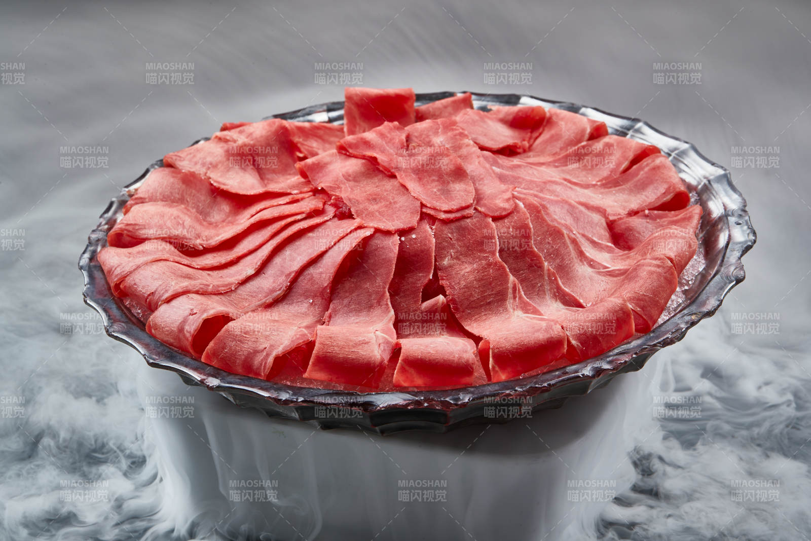 干冰缭绕的背景上摆放的鲜牛肉刺身图片