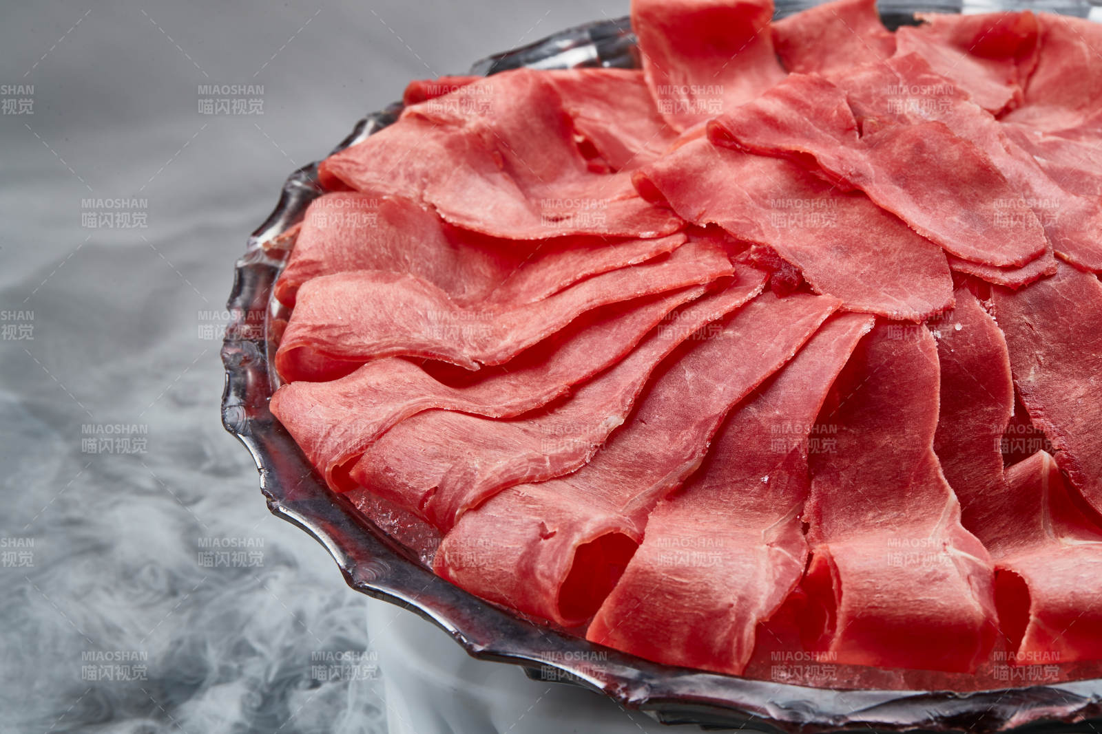 干冰缭绕的背景上摆放的鲜牛肉刺身图片