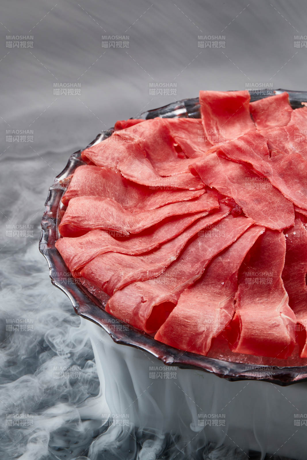 干冰缭绕的背景上摆放的鲜牛肉刺身图片